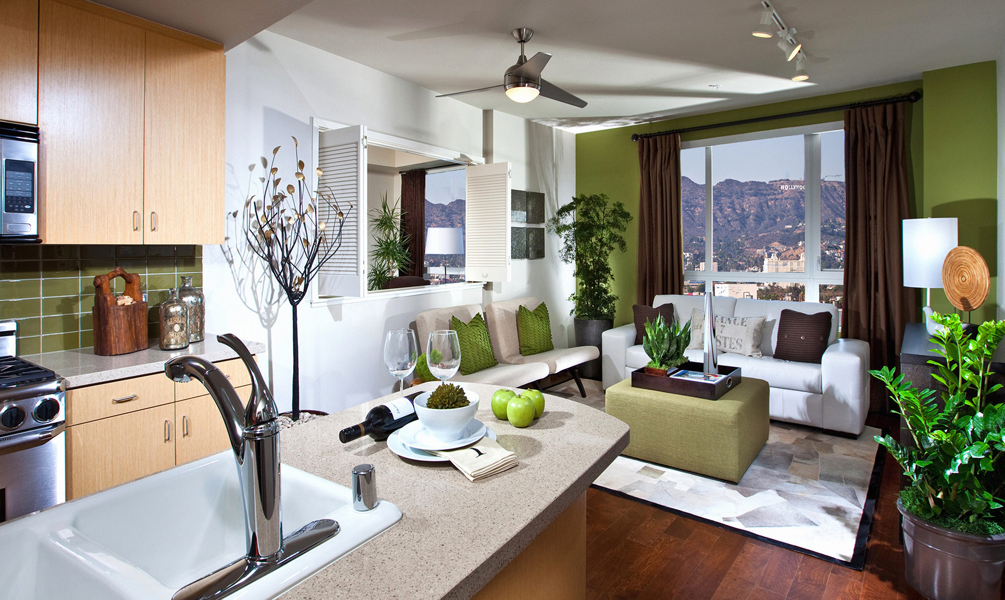 Interior of fully furnished kitchen and living space with green accents and large window.