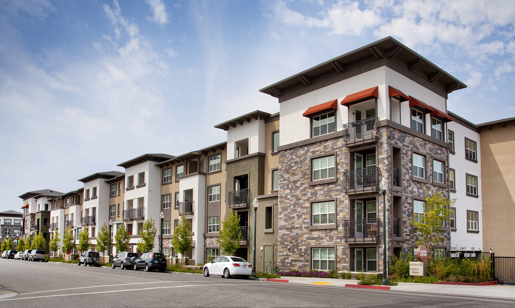 Front view of walk up with varying green, tan and stone along the facade